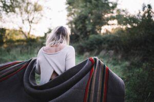 woman uses blanket to warm up outside