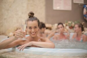 friends celebrating an occasion with champagne in a hot tub